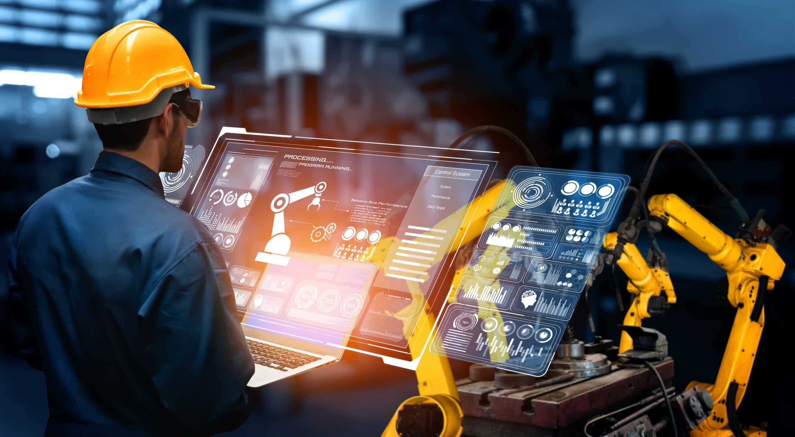 An industrial engineer wearing a safety helmet operates a Process Control System on a digital interface to monitor and manage robotic arms in an automated factory.
